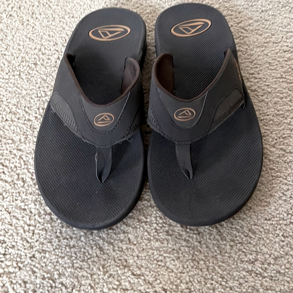 Size 10reef flip flops with beer opener on bottom. NEVER BEEN WORN. Dark Brown